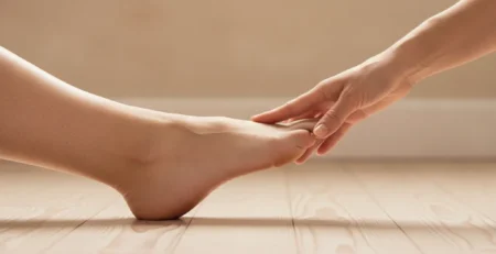 Žena si drží prednú časť chodidla, kde pri metatarzalgii vzniká bolesť prednožia.