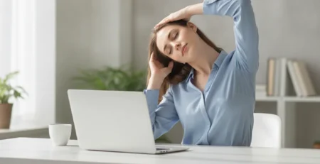 Žena pri pracovnom stole naťahuje krk nakláňaním hlavy k ramenu počas prestávky v práci.